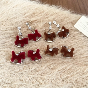 Detailed close-up of flocked pony earrings with zircon accents on soft plush background
