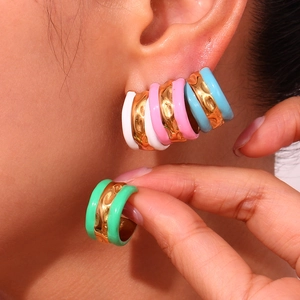 Detailed macro view of colorful enamel C-shape hoop earrings in pastel shades and gold finish