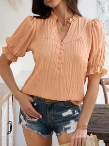 Close-up of orange short sleeve shirt featuring ruffled cuffs and a small stand collar