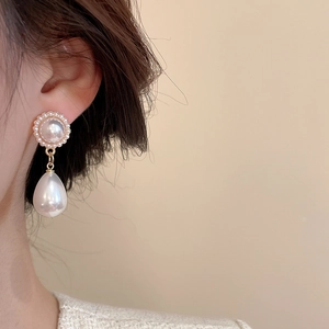 Detailed close-up of vintage teardrop pearl earrings with gold metallic finish
