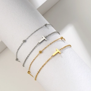 Detailed view of dual-layer gold and silver steel bracelets with T-pendants and metal beads