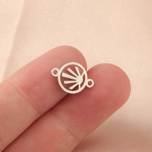 Polished stainless steel circular sunburst charm held between fingers for size reference