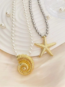 Detail of gold starfish and conch pendants on layered pearl and metal bead necklaces