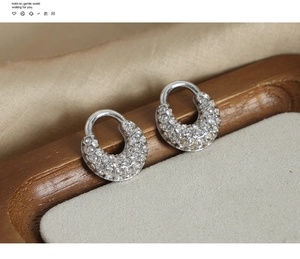 Vue macro de boucles d'oreilles en U argentées avec cristaux pavés sur plateau