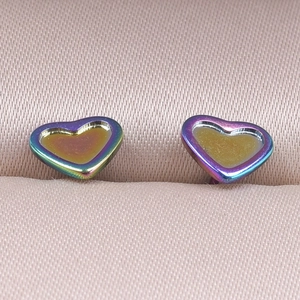 Macro shot of heart-shaped stainless steel earrings with iridescent finish and amber resin
