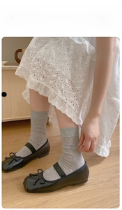 Detail of grey crew socks with bow embroidery styled with black Mary Jane shoes