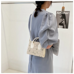 Model view showing the back profile of the embroidered straw handbag with floral details