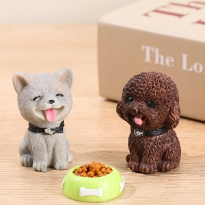 Miniature resin puppy figurines in grey and dark brown with a small green food bowl