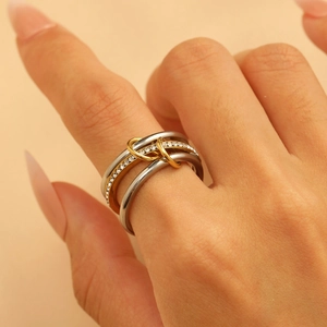 Close-up of interlocking gold and silver rings with cubic zirconia pave on fingers