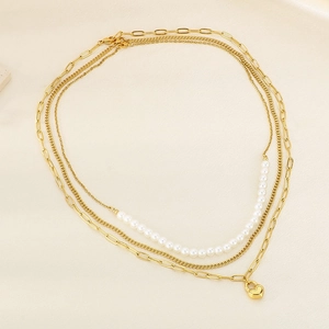 Macro detail of triple-layer gold necklace featuring heart pendant and pearl strand