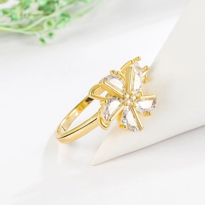 Rotating zircon windmill ring in golden finish on white display stand with green plant
