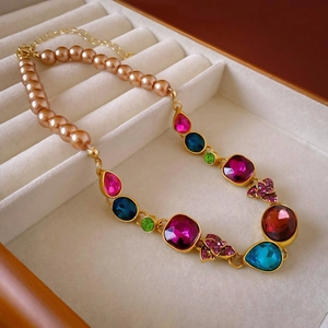 Detailed view of luxury necklace with colorful rhinestones and pearls in a beige jewelry box