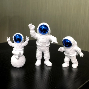 Three resin astronaut figurines in white and blue, posed on a lunar surface base