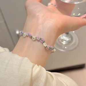 Sweet floral beaded bracelet with purple and white flower beads on a model wrist