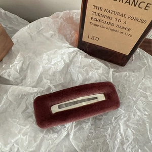 Close-up of a burgundy velvet rectangular hair clip on a textured white background
