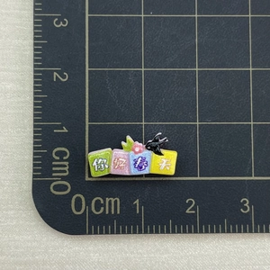 Mini resin nail art accessory measuring 2.8cm on a black metric cutting mat grid