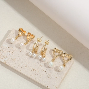 Vintage gold hollow heart earrings set with white pearls on a minimalist stone base