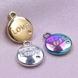 Close-up of LOVE engraved stainless steel pendants on pink silk for DIY jewelry making