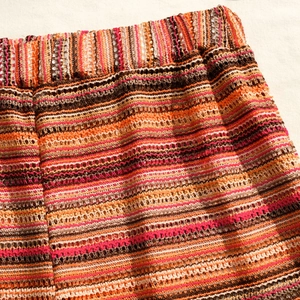 Detail of colorful striped hollow crochet knit mini skirt with elastic waist texture