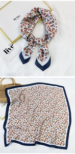 Detail view of square floral silk scarf with red and blue patterns and navy blue border