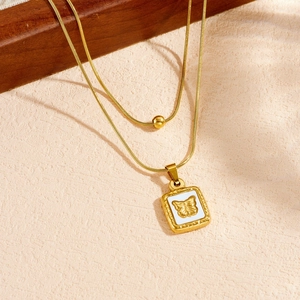 Gros plan détaillé d'un collier doré multicouche avec pendentif papillon blanc carré