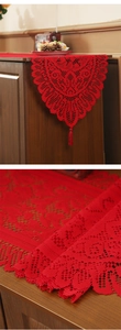 Close-up of red Christmas lace table runner featuring crochet floral patterns and tassels