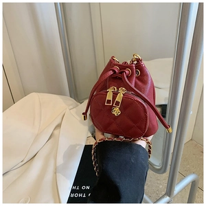 Detail of red quilted mini bucket bag with gold flower emblem and chain strap