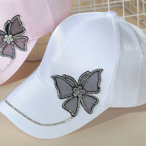 Detail of white and pink baseball caps with mesh butterfly lace and sparkling rhinestones