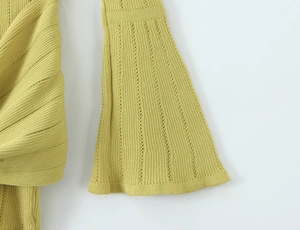 Gros plan détaillé des manches évasées et motifs ajourés sur la robe jaune moutarde