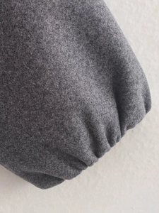 Détail de la veste en laine gris foncé montrant les poignets plissés élastiques et doux