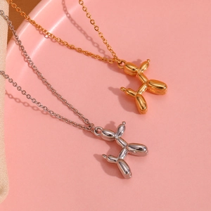Detail shot of gold and silver balloon dog pendants on fine chains over a pink background