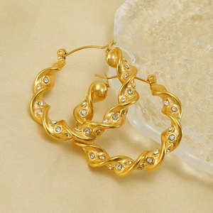 18k gold plated twisted hoop earrings with sparkling white rhinestones on silk background