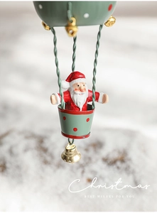 Macro detail of Santa Claus in a green hot air balloon ornament with a gold metal bell