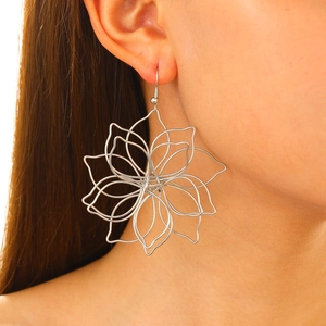 Detail shot of large silver wire-wrapped hollow flower earrings worn on model's ear