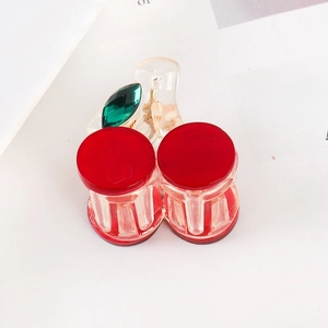 Close-up of a red cherry hair claw clip with transparent resin and a green gemstone leaf
