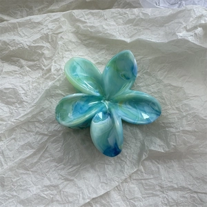 Detailansicht der blauen Marmor-Blumen-Haarklammer auf weichem weißem Papier