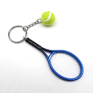 Detail of creative blue tennis racket and yellow ball keychain charm on white background