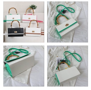 Detail of crocodile pattern handbag featuring a bamboo top handle and detachable strap