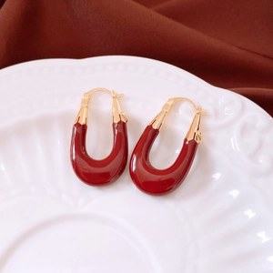 French vintage burgundy U-shaped earrings on an embossed white porcelain plate
