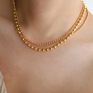 Close-up of triple-layered gold ball necklace featuring polished beads in varied sizes