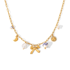 Detail of gold necklace with moon, bow, and sun charms featuring pearls and ceramic beads