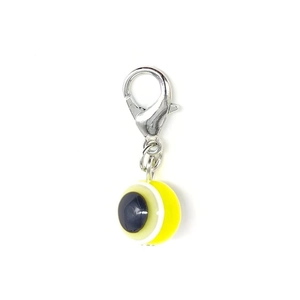 Macro shot of yellow and black resin evil eye charm with a silver lobster clasp