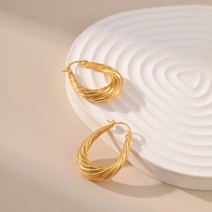 Classic 18K gold plated brass twisted hoop earrings on a white stone rippled base