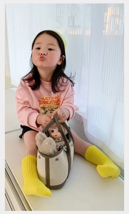 Toddler wearing yellow mid-calf cotton socks and holding a canvas mini bucket handbag