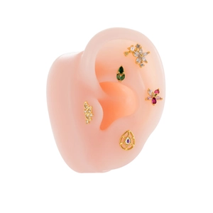 Golden flower and bow cartilage studs set with multi-colored cubic zirconia on a model