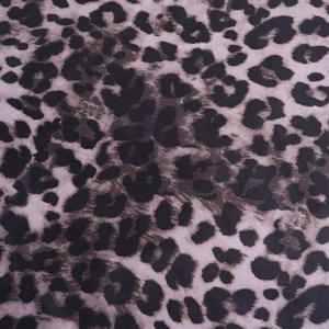 Close-up of leopard print fabric with black, dark brown, and light purple spotted patterns
