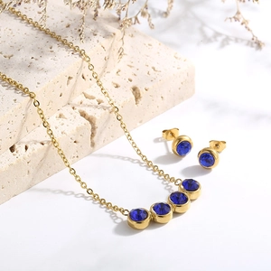 Detailed shot of titanium steel jewelry set with blue zircons on beige travertine stone