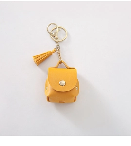Detail of yellow PU leather mini bag case with metal key ring and tassel for AirPods