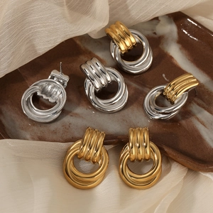 Interlocked geometric hoop earrings in gold and silver finish on a ceramic plate