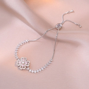 Detail of adjustable silver clover bracelet with pink zircons on silk background